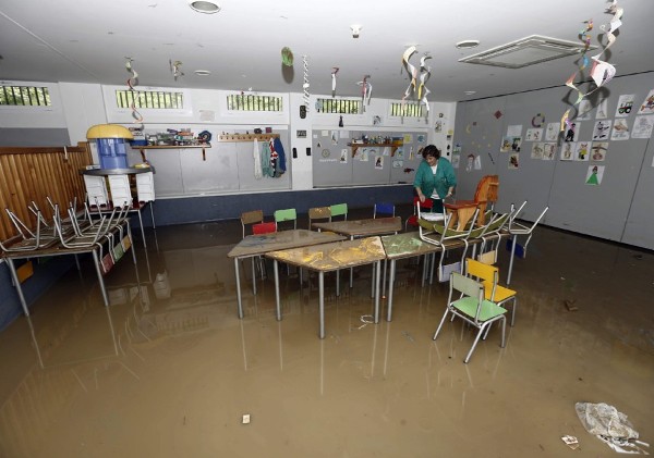 Una trabajadora del Club Deportivo Amaya limpia una habitación para los más pequeños, que se encuentra totalmente inundada tras el desbordamiento ayer del río Arga. 