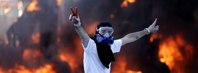 Un manifestante hace el signo de victoria frente a una excavadora incendiada durante un enfrentamiento contra la policía antidisturbios, en la plaza Taksim de Estambul (Turquía).