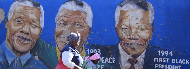 Una mujer y su hija pasan junto a un mural del expresidente sudafricano Nelson Mandela, en Soweto, Johanesburgo.