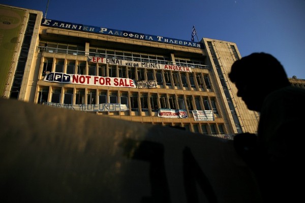 Un manifestante sostiene un cartel frente a la sede de la televisión pública griega ERT en Atenas.