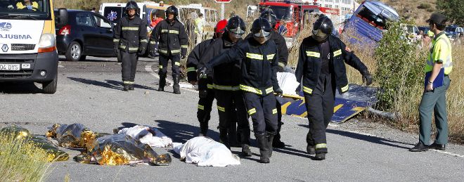 Efectivos del cuerpo de bomberos trasladan a los fallecidos en el accidente de autocar ocurrido en torno a las 08.30 horas de hoy en la N-403, en Tornadizos.