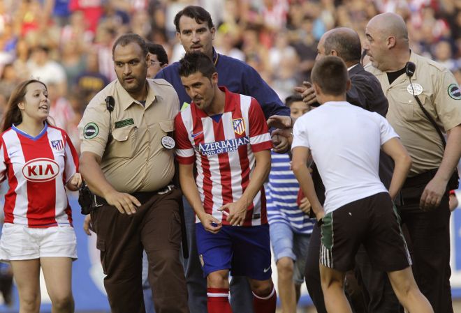 David Villa sale custodiado del Vicente Calderón tras su presentación.