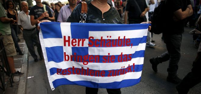 Una mujer muestra una bandera nacional griega con el eslogan 