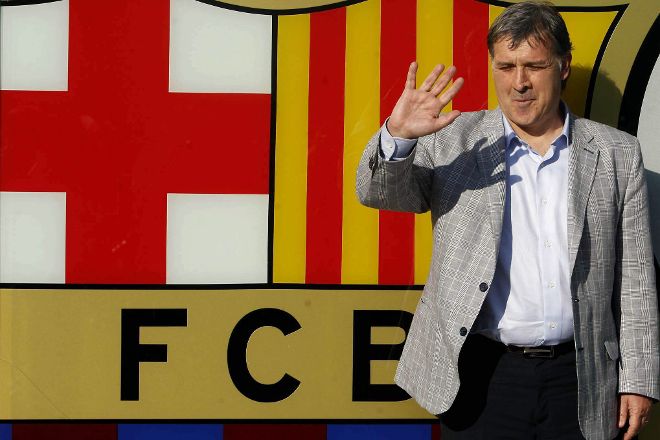 El nuevo entrenador del F.C.Barcelona, el argentino Gerardo 'Tata' Martino, posa ante el escudo barcelonista.