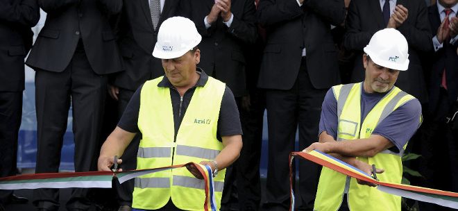Un trabajador rumano y otro búlgaro cortan una cinta durante una inauguración oficial.