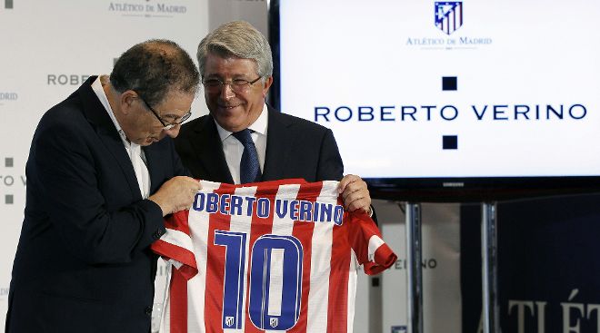 El presidente del Atlético Madrid, Enrique Cerezo (d), entrega una camiseta del equipo al diseñador Roberto Verino.