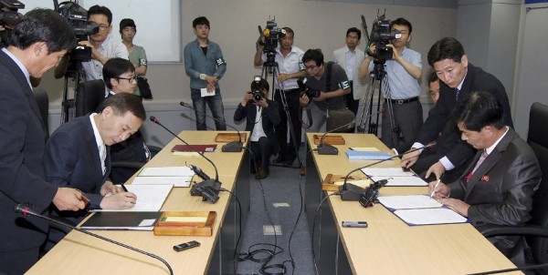 Fotografía facilitada por el gobierno coreano que muestra al representante por parte de Seúl, Kim Ki-woong (c-d), mientras firma un acuerdo junto a su homólogo norcoreano Park Chul-Soo (c-ii), durante su encuentro en el complejo industrial de Kaeseong, en Corea del Norte.