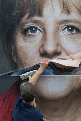 Un trabajador pega un cartel electoral de Angela Merkel.