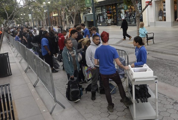 Dos empleados de Apple hablan con los consumidores mientras aguardan la fila a las puertas de una tienda Apple de Santa Monica, California.