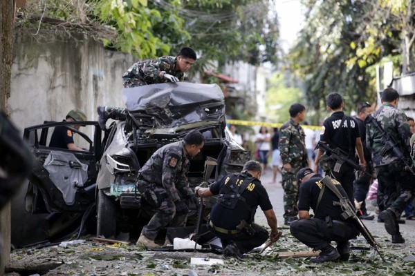 Policías y soldados filipinos inspeccionan un coche dañado en lo que se sospecha ha sido un ataque con mortero.
