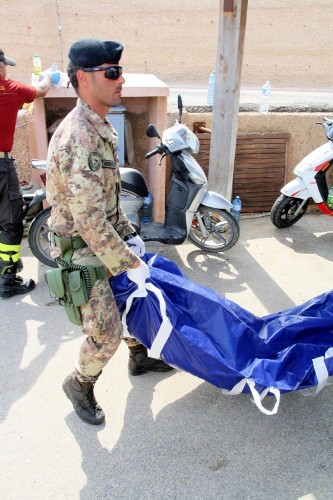 Fotografía facilitada por la Armada de Italia que muestra a un militar que traslada el cuerpo de uno de los inmigrantes muertos.