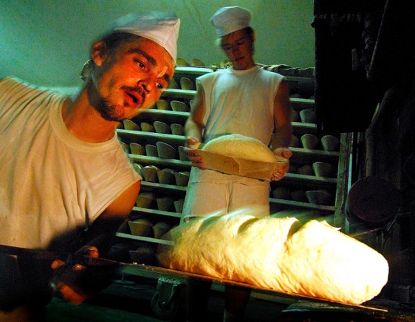 Un panadero mete en el horno una barra de pan.