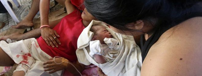 La recién nacida Bea Joy (c) es cogida en brazos por su tía después de llegar al mundo en medio de las ruinas de un edificio que resultó dañado por el paso del tifón 