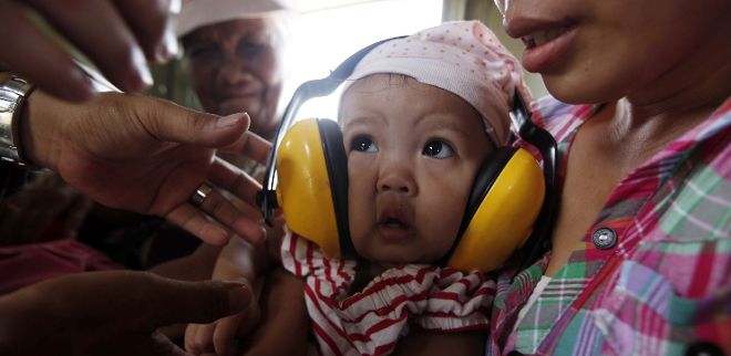 Una madre filipina protege con cascos a su bebé enfermo tras ser evacuados de la ciudad de Tacloban, en la provincia de Leyre (Filipinas).