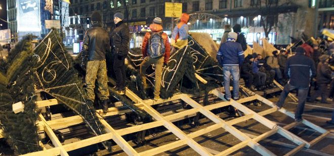 Manifestantes construyen una barricada en la plaza de la independencia en Kiev (Ucrania) en la madrugada de hoy, lunes 2 de diciembre de 2013. Grupos de manifestantes se dirigieron hoy hacia la sede del Gobierno de Ucrania con el propósito de bloquear sus accesos para exigir la dimisión del primer ministro Nikolái Azárov, tras una noche de tensa calma en la capital ucraniana, escenario ayer de violentos enfrentamientos. arios miles de manifestantes pasaron la noche en la Plaza de la Independencia, donde levantaron barricadas para rechazar un eventual intento de desalojo por la policía antidisturbios.
