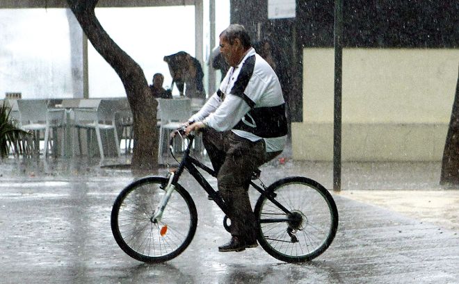 Un ciclista pasea por el centro de la capital tinerfeña bajo la lluvia.