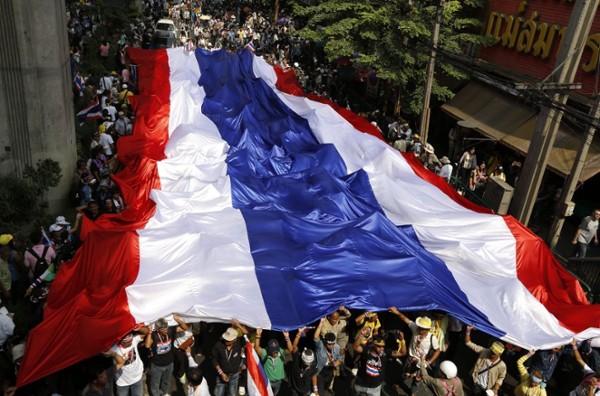 Manifestantes antigobierno portan una bandera tailandesa gigante durante una marcha protesta hasta las oficinas del Gobierno en Bangkok (Tailandia), hoy, lunes 9 de diciembre de 2013. El Gobierno de Tailandia anunció hoy la disolución del Parlamento y la celebración de elecciones generales dentro de 60 días tras el disolver el Legislativo con el objetivo de atenuar las protestas antigubernamentales previstas este lunes.