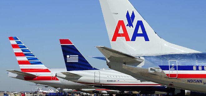 Fotografía de archivo fechada el 14 de febrero de 2013 que muestra un avión de la aerolínea US Airways (c), junto a otros dos de la aerolínea American Airlines (i, d), en el aeropuerto Dallas-Fort Worth, en Ft. Worth (Texas), Estados Unidos.