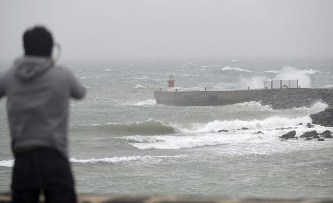 Una persona observa las olas que rebasan la altura de los diques en el puerto de Arrecife (Lanzarote), ayer.