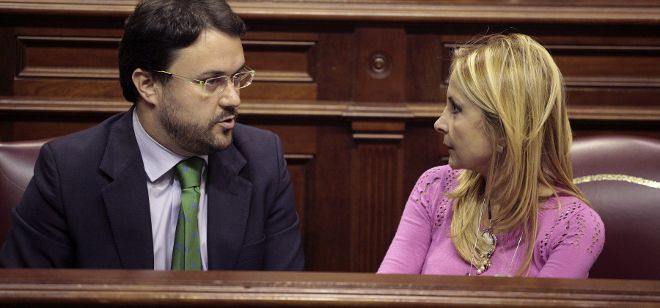 El portavoz del grupo parlamentario popular, Asier Antona, conversa con su compañera de partido, María Australia Navarro durante un pleno del Parlamento de Canarias.