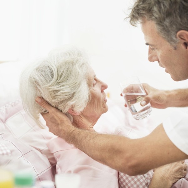 male nurse helping an old woman drink a glass of water 56570566