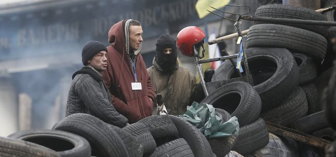 Unos manifestantes permanecen de pie en una barricada en la calle Grushevskogo, en el centro de Kiev, Ucrania, hoy, lunes 17 de febrero de 2014. La ley de amnistía que beneficia a más de 230 manifestantes detenidos en las protestas populares en Ucrania entró hoy en vigor con su publicación en la página web de la Fiscalía General ucraniana. La entrada en vigor la amnistía se produjo después de que ayer la oposición ucraniana desalojara el Ayuntamiento de Kiev, tras dos meses y medio de ocupación.