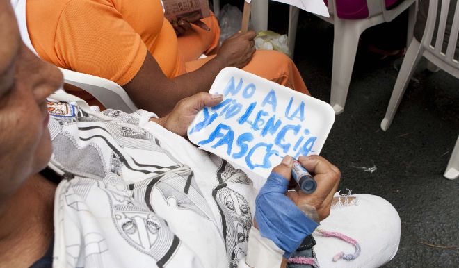 Una mujer escribe un letrero contra la violencia.