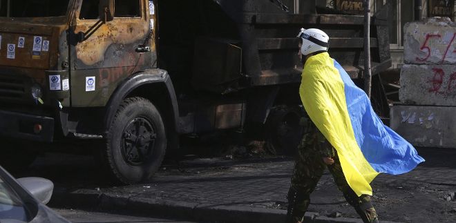 Un manifestante camina junto a un camión destrozado durante las protestas de Kiev, Ucrania, el 24 de febrero del 2014. Un grupo de radicales ucranianos amenaza hoy con asaltar la Rada Suprema (Legislativo), si las nuevas autoridades no liberan a sus partidarios detenidos durante los tres meses de protestas antigubernamentales.