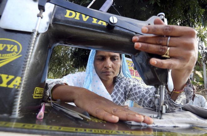 Una mujer india trabaja con una máquina de coser en un arcén de una carretera .