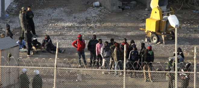 Inmigrantes subsaharianos rodeados por la Policía marroquí, hoy en el perímetro fronterizo entre Ceuta y Marruecos.