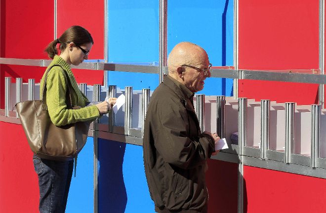 Dos personas eligen sus papeletas para votar.