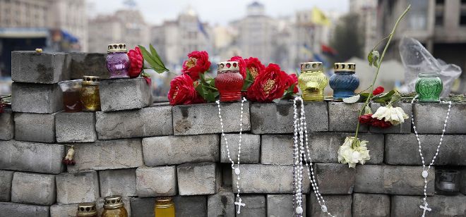 Fotografía que muestra varias flores, velas y rosarios que han sido depositados por partidarios del movimiento popular que derrocó a Víktor Yanukóvic.