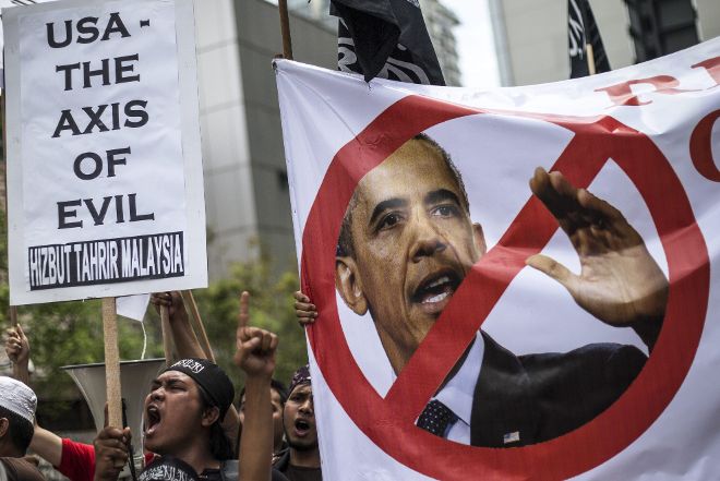 Activistas malasios sostienen pancartas y gritan consignas contra el presidente de EE.UU., Barack Obama.