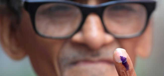 Un votante indio muestra su dedo con tinta después de realiar el voto.
