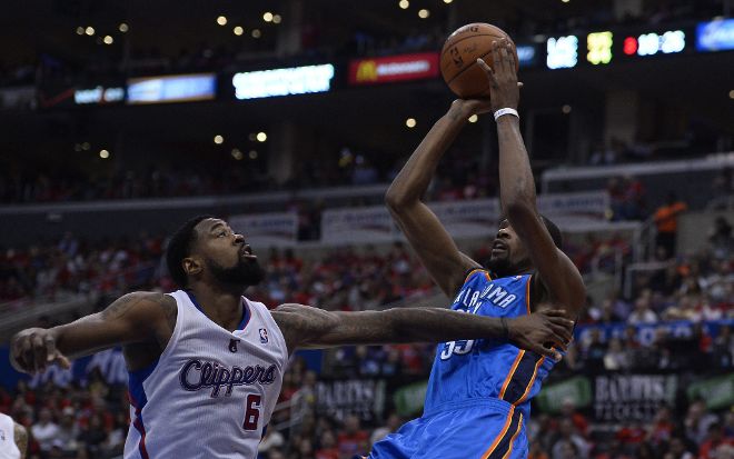 El jugador de los City Thunder Kevin Durant (dcha) salta para encestar mientras DeAndre Jordan (izda) de los Clippers.