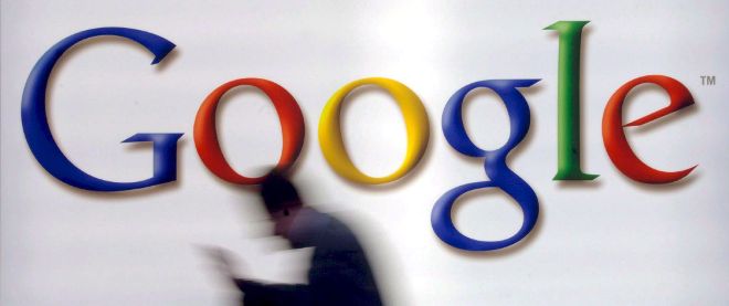 Fotografí que muestra un hombre pasando por delante de un logo de Google.