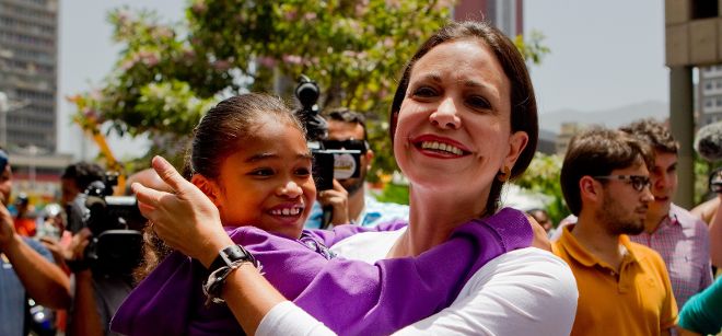 La exdiputada y dirigente de oposición, María Corina Machado (c), abraza a una niña en las inmediaciones del Palacio de Justicia.