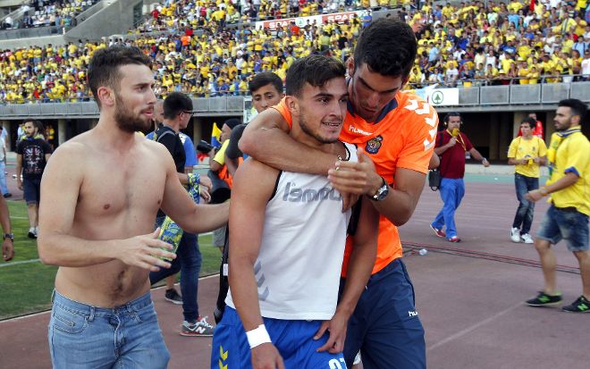 Aficionados treatan de consolar al jugador de la UD Las Palmas Ángel (c), al término del partido.