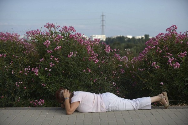 Una mujer israelí se cubre la cabeza y se tumba en el suelo mientras suenan las sirenas en la ciudad meridional de Ashdod (Israel) hoy, miércoles 9 de julio de 2014.