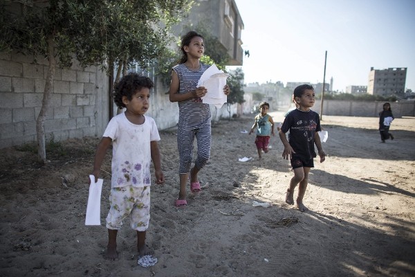 Niños palestinos corren para recoger los panfletos lanzados por las Fuerzas de Defensa sobre el barrio de Shuja'iyya, al este de Gaza capital, hoy, miércoles 16 de julio de 2014. 