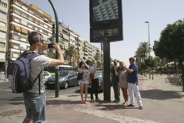 Un grupo de turistas se hacen una foto de recuerdo bajo un termómetro del centro de Córdoba.