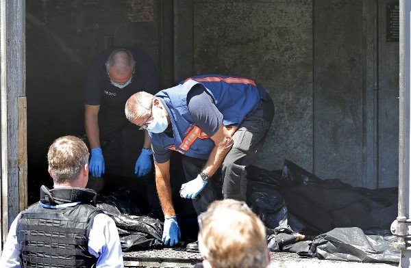 Expertos forenses holandeses conversan con inspectores de la OSCE mientras revisan las bolsas de los cadáveres de las víctimas del vuelo MH17 acumuladas en un vagón refrigerado en una estación de tren de Torez, a unos 90 kilómetros al este de Donetsk (Ucrania).