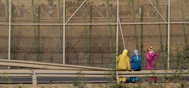 Tres mujeres observan a un grupo de inmigrantes que permanece en el lado marroquí.