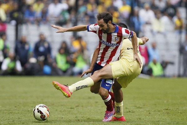 El jugador del Atlético de Madrid Juanfran Torres (i) disputa el balón con Raúl Alonso Jiménez (d) de América.