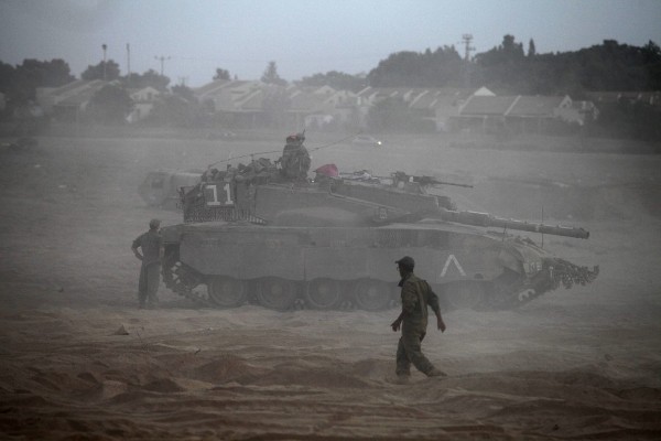 Soldados israelíes caminan cerca a un tanque Merkava.
