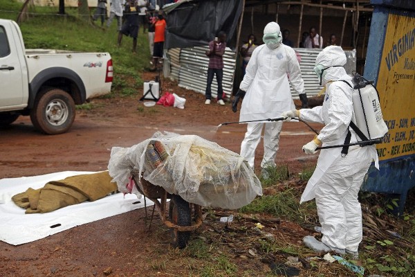 Varias enfermeras liberianas desinfectan una víctima del ébola en la calle en una calle en Virginia, a las afueras de la capital Monrovia, en Liberia.
