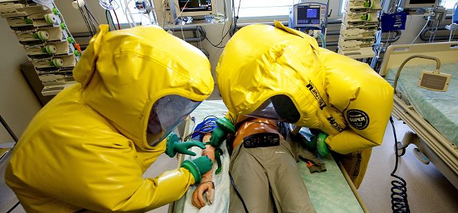 Personal militar viste con trajes especiales mientras trabajan en la simulación de un caso de enfermo de un virus contagiosO.
