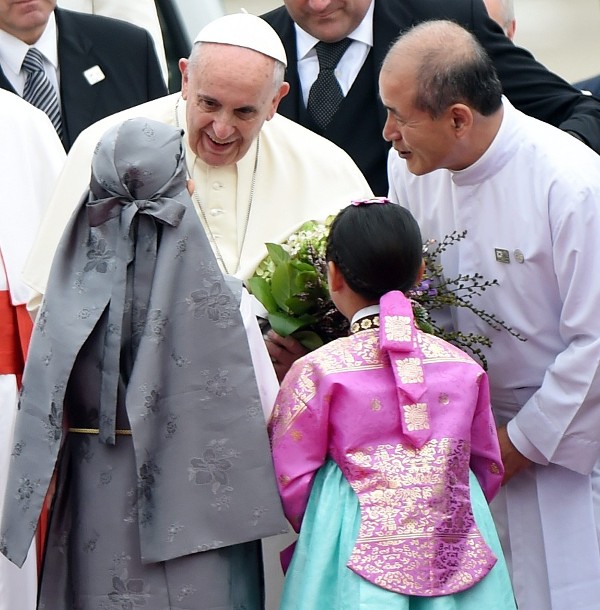 El papa Francisco (de frente) recibe flores de una niña acompañado de la presidenta de Corea del Sur Park Geun-Hye (fuera de cuadro) a su llegada hoy, jueves 14 de agosto de 2014, al aeropuerto de Seúl en Seongnam (Corea del Sur).