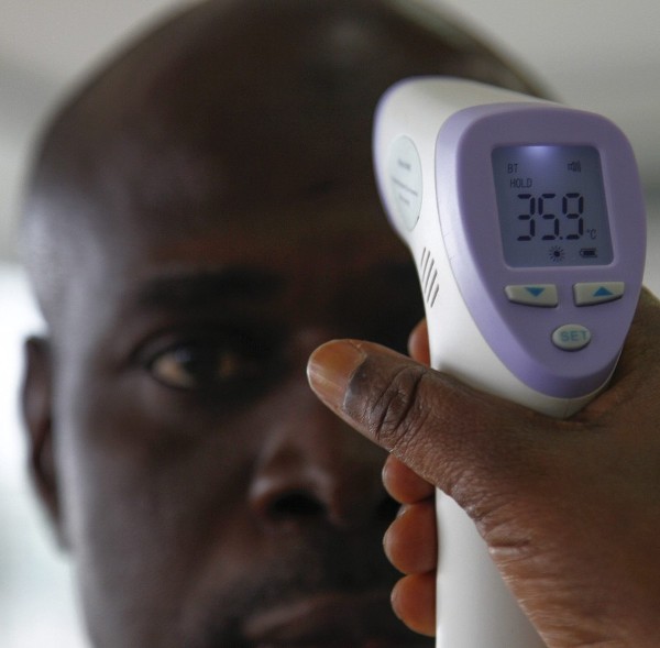 Un voluntario del Instituto Nacional de Salud Pública mide la temperatura de los viajeros como precaución sobre el ébola.