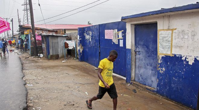 Un liberiano pasa ante una escuela de West Point, donde pacientes de ébola alojados sufrieron un ataque de manifestantes. 